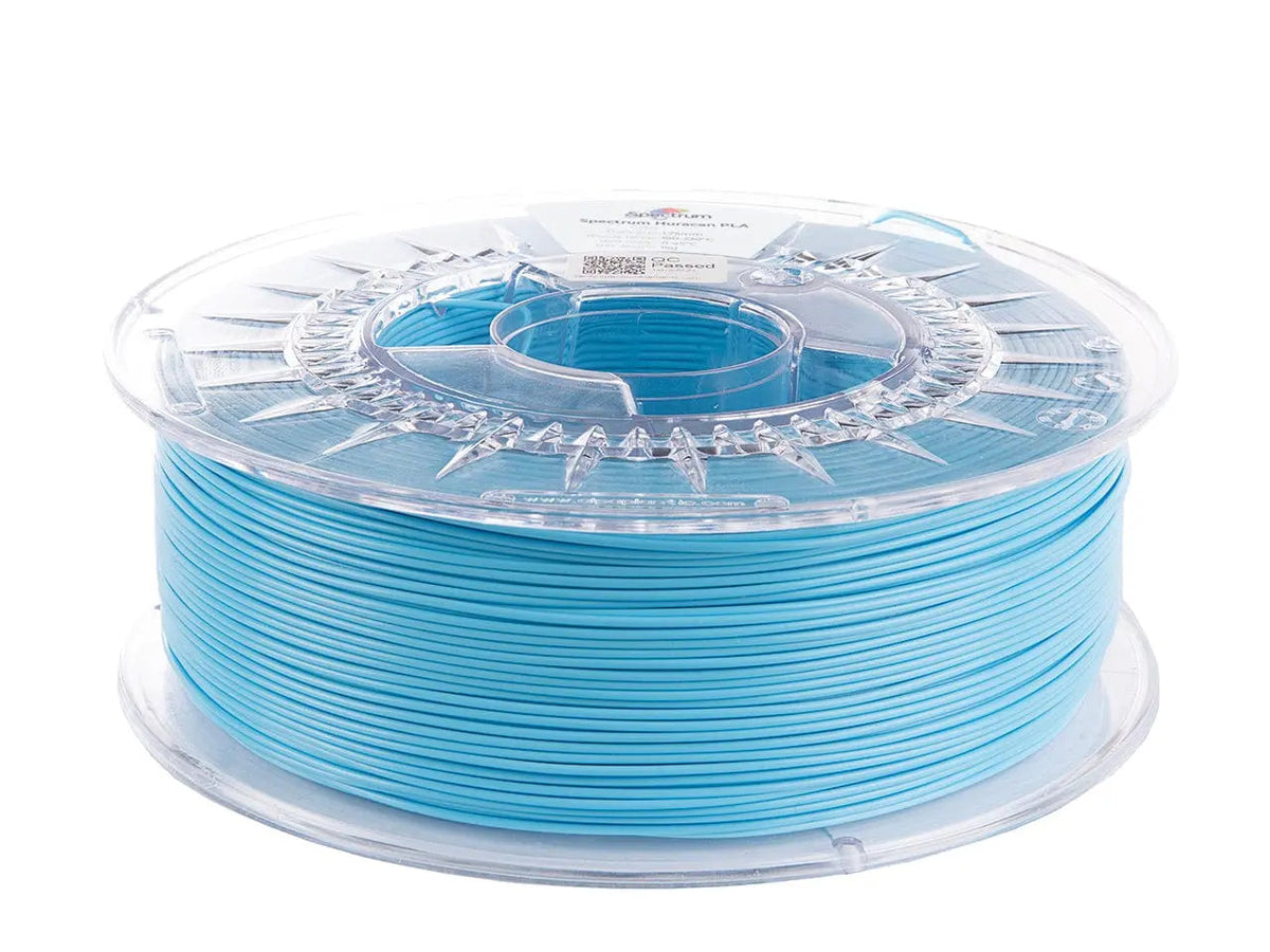 Bobine de filament PLA bleu bébé dans une bobine plastique transparente, vue de trois quarts sur fond blanc