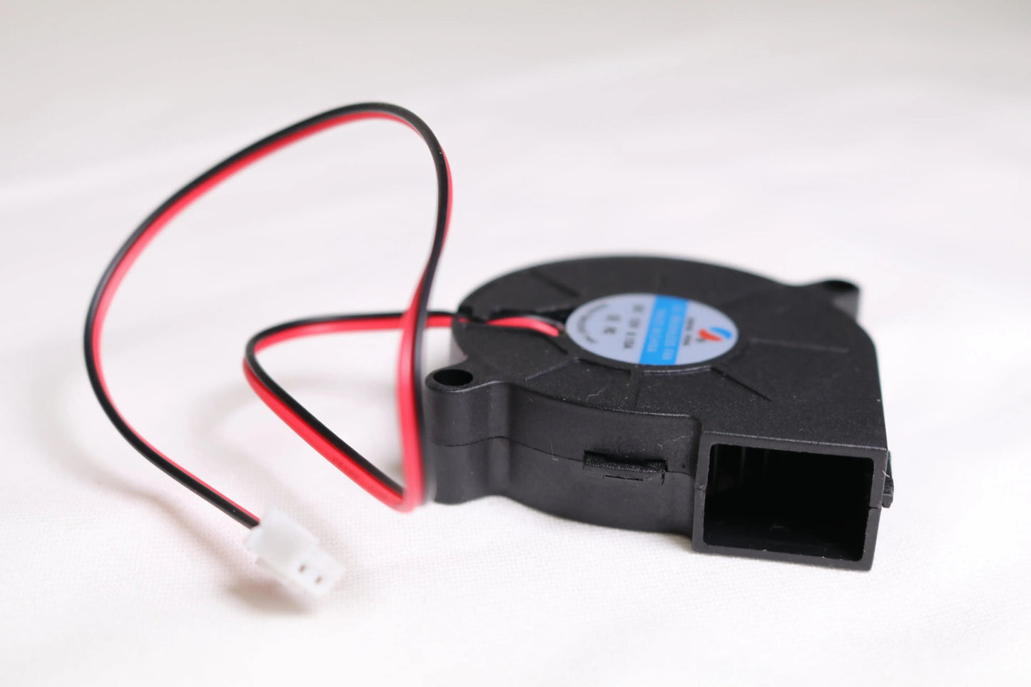 Vue en angle d’un petit ventilateur soufflant noir 5015 avec câbles rouge et noir et connecteur blanc