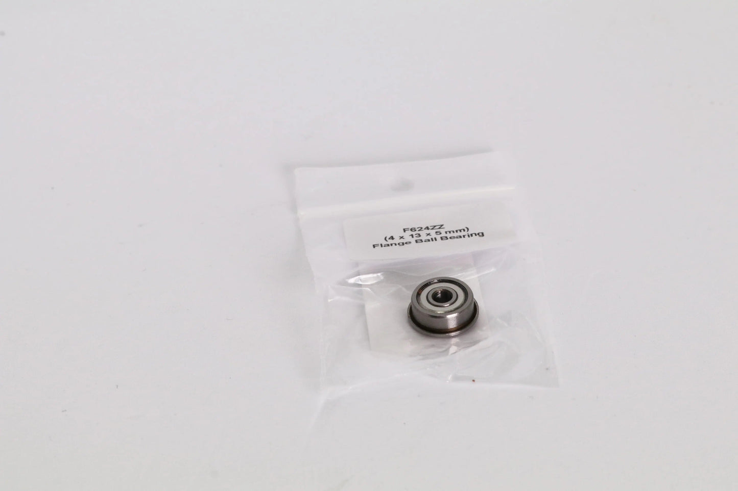 Petit roulement à billes dans un sachet plastique transparent avec étiquette, posé sur fond blanc