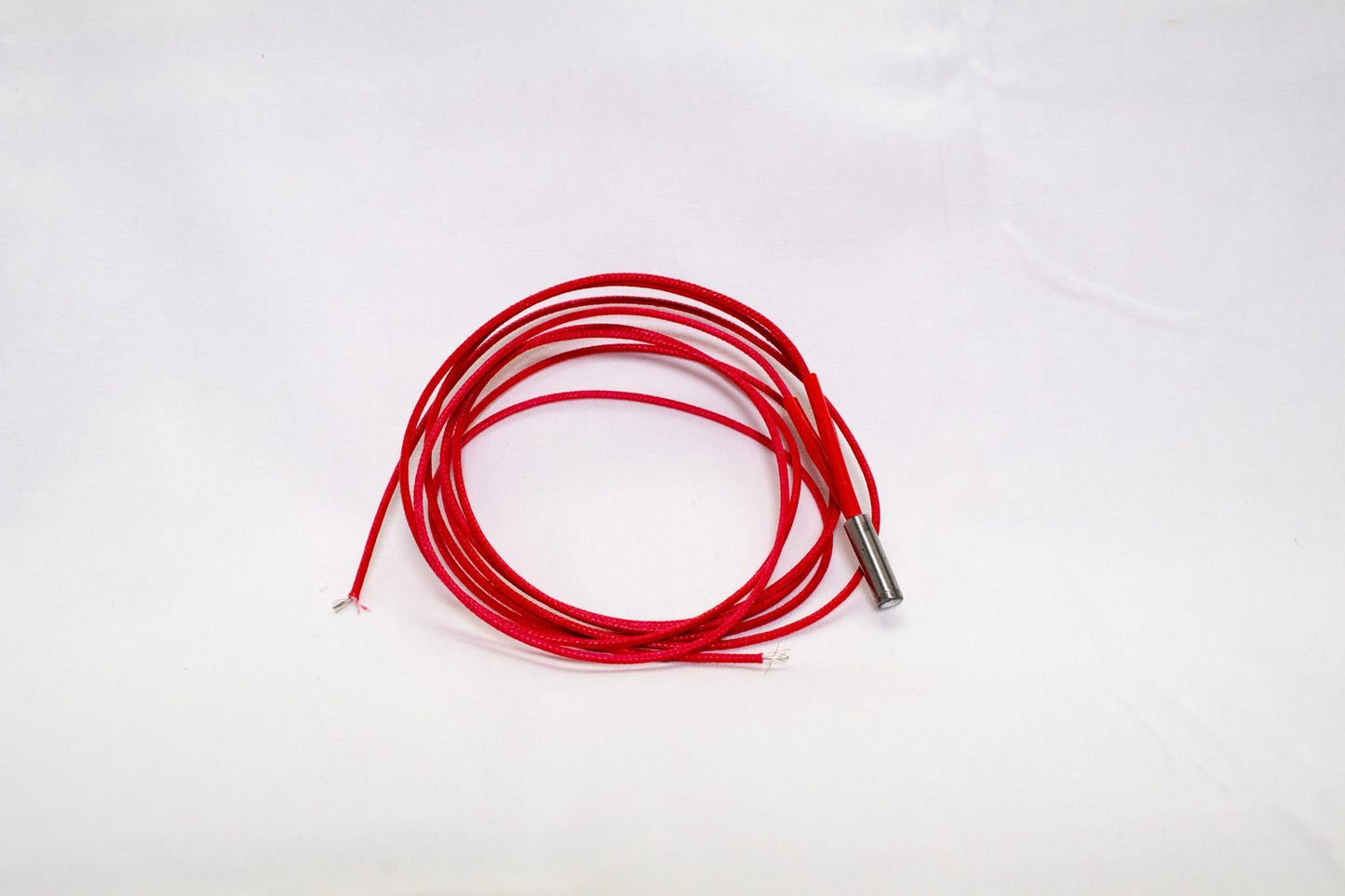 Cartouche chauffante rouge enroulée, avec embout métallique visible sur fond blanc