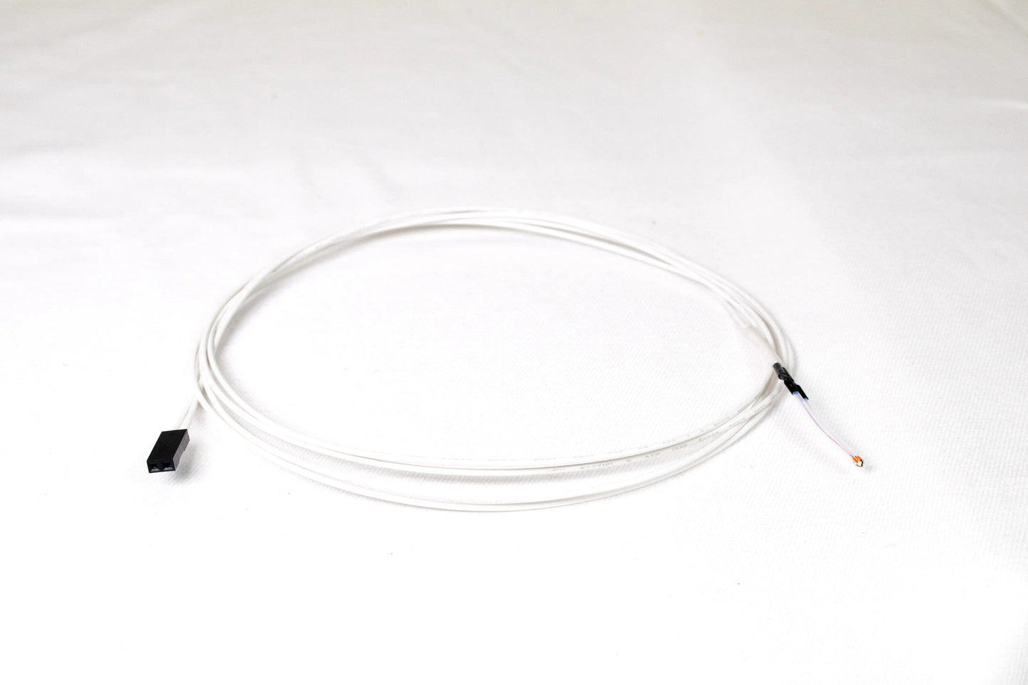 Un capteur thermistor blanc enroulé sur fond blanc, avec un connecteur Dupont noir à une extrémité et deux fils dénudés à l’autre