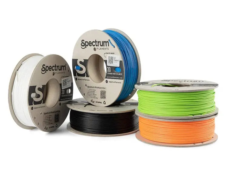 Cinq bobines de filament Spectrum, en blanc, bleu, noir, vert et orange, disposées sur fond blanc