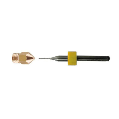 Gros plan d’un petit foret de nettoyage noir avec bague jaune, à côté d’une buse en laiton dévissée