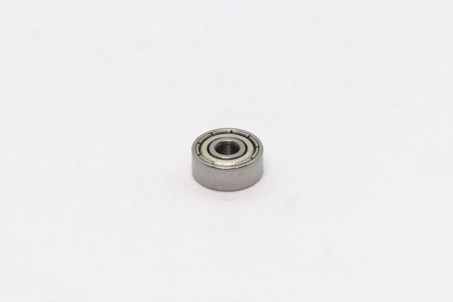 Un petit roulement à billes métallique vu de dessus sur fond blanc