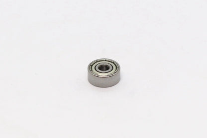 Un petit roulement à billes métallique vu de dessus sur fond blanc
