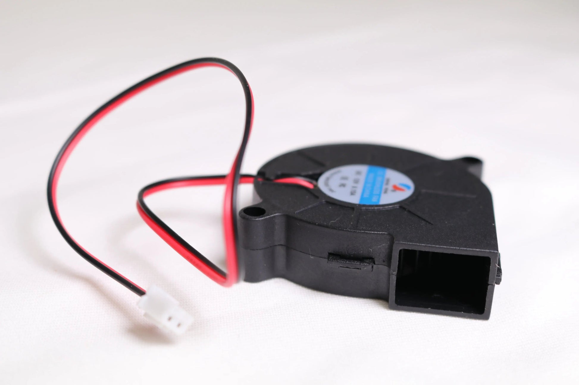 Vue en angle d’un petit ventilateur soufflant noir 5015 avec câbles rouge et noir et connecteur blanc