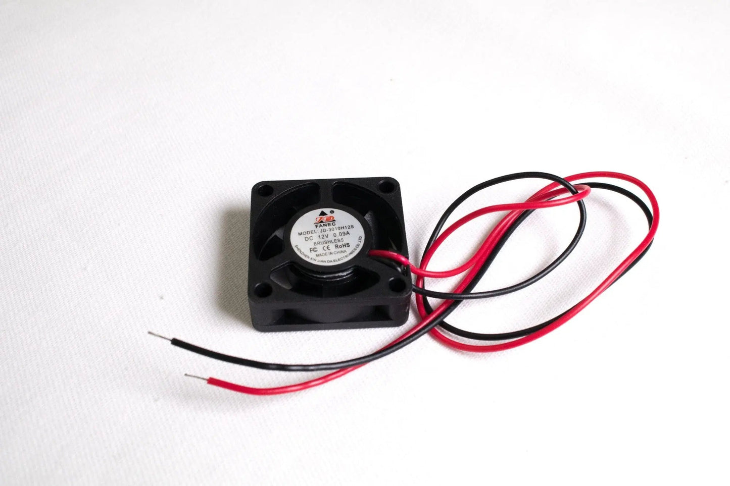 Petit ventilateur carré noir avec fils rouge et noir dénudés sur fond blanc