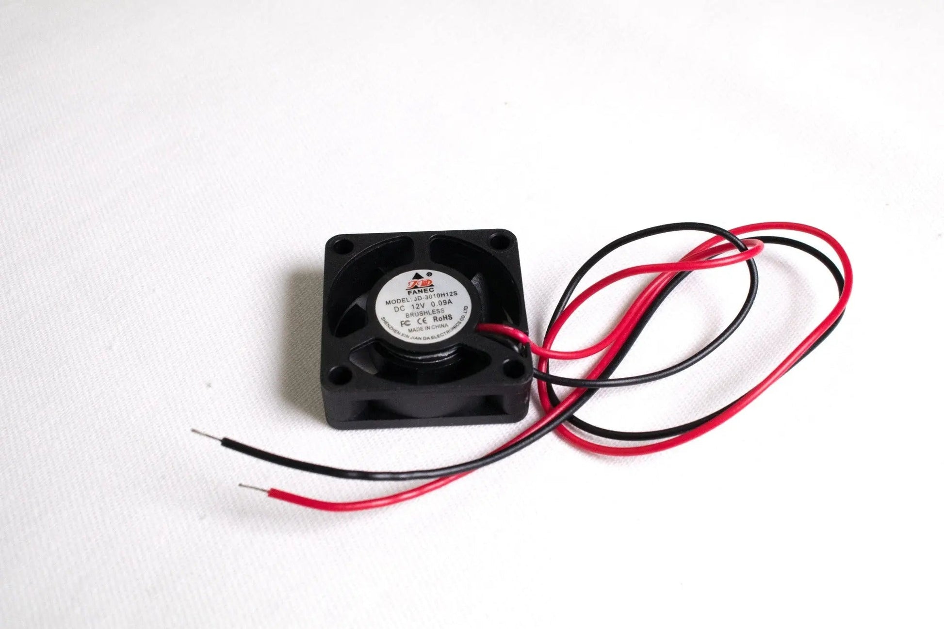Petit ventilateur carré noir avec fils rouge et noir dénudés sur fond blanc
