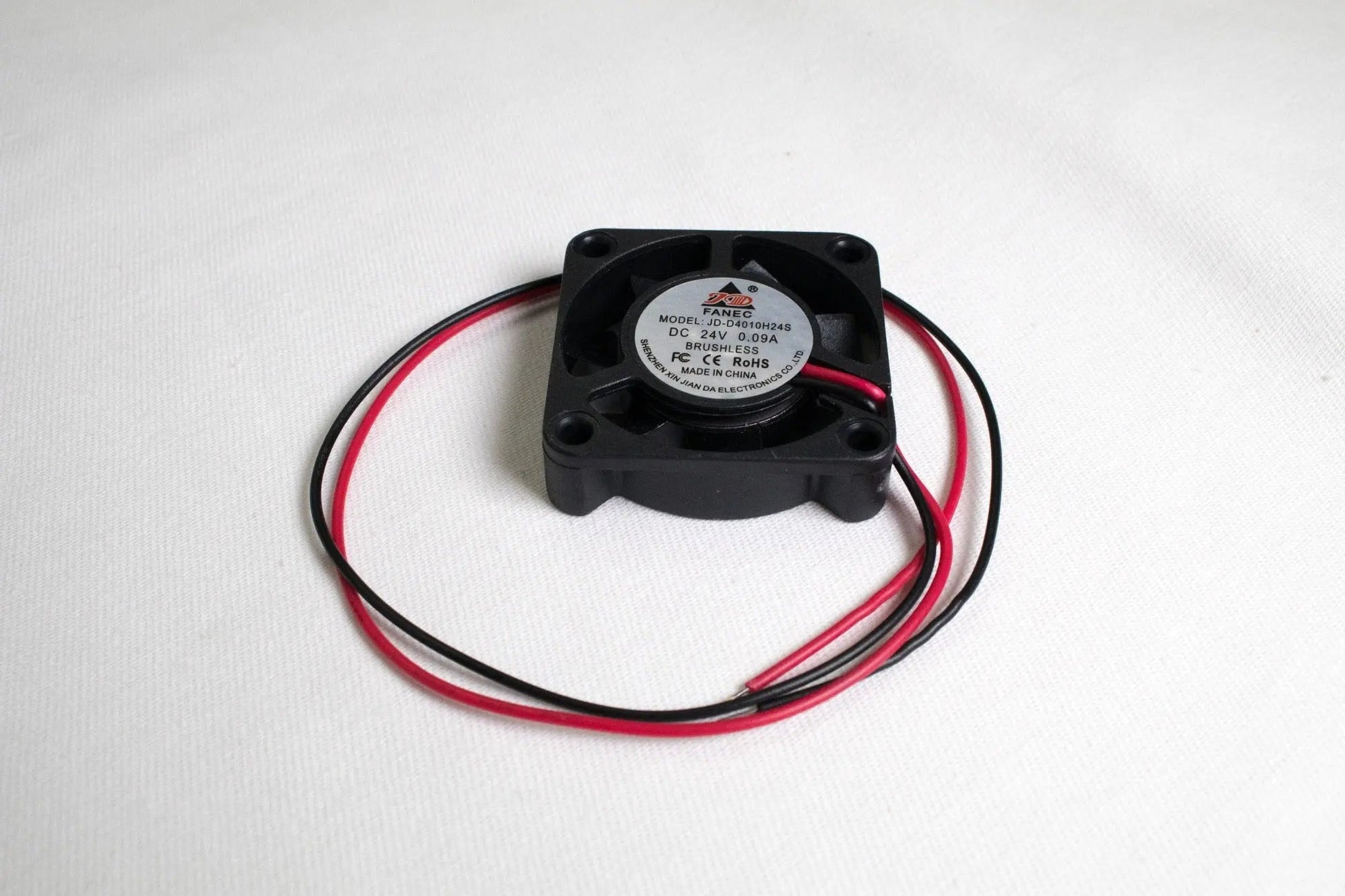 Petit ventilateur carré noir avec deux fils rouge et noir enroulés sur fond blanc