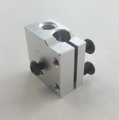 Bloc chauffant en aluminium argenté, vu en biais sur fond blanc, avec vis noires et trous filetés visibles