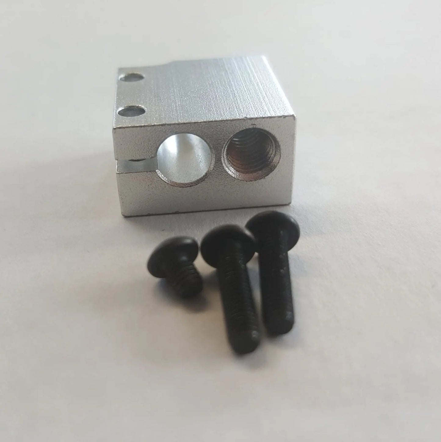 Bloc chauffant en aluminium argenté vu de face, avec trois vis noires au premier plan