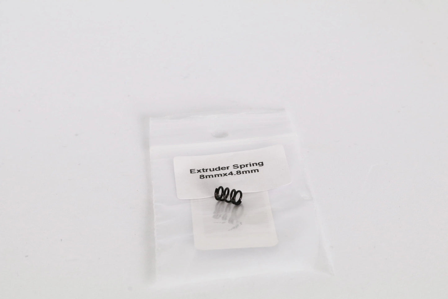 Petit sachet plastique transparent contenant un ressort noir, avec étiquette « Extruder Spring 8mmx4.8mm »