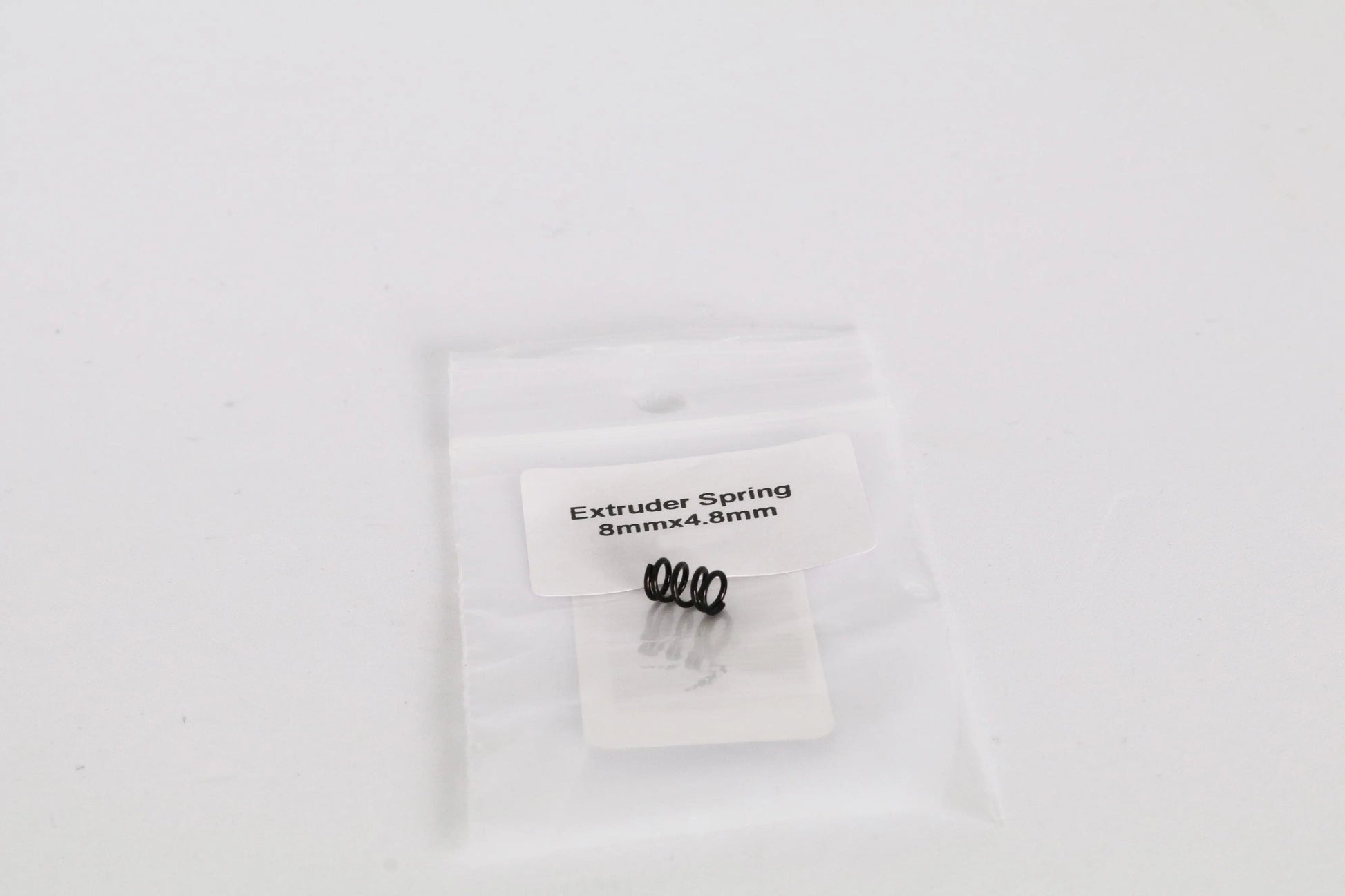 Petit sachet plastique transparent contenant un ressort noir, avec étiquette « Extruder Spring 8mmx4.8mm »