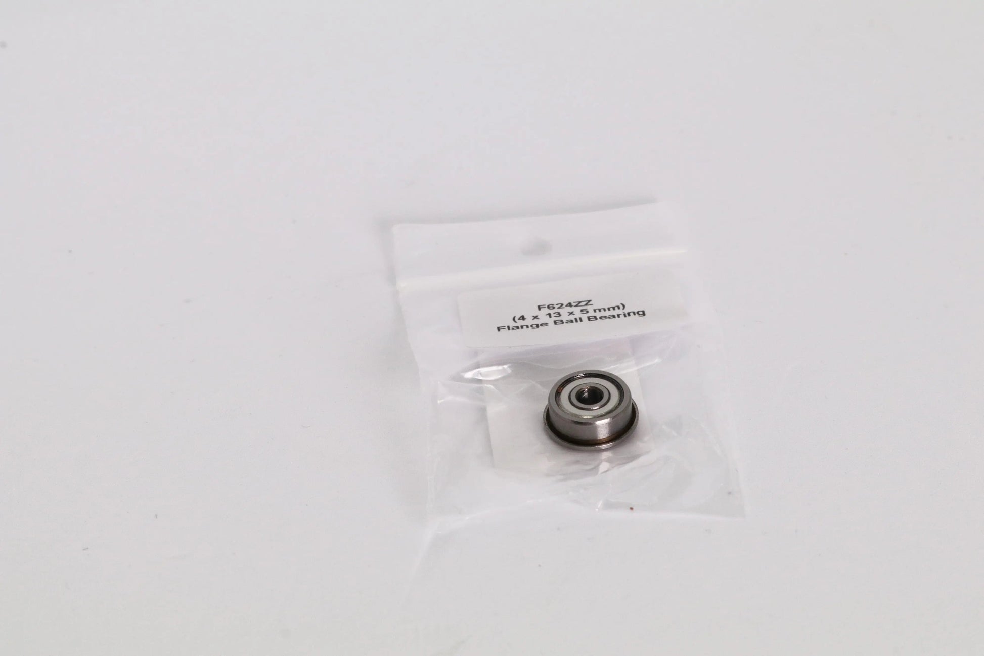 Petit roulement à billes dans un sachet plastique transparent avec étiquette, posé sur fond blanc