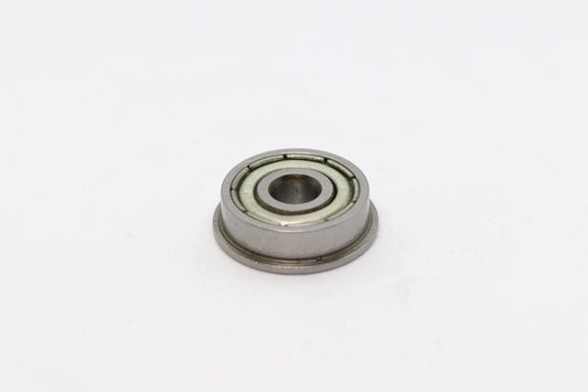 Vue rapprochée d’un petit roulement à billes à bride métallique sur fond blanc