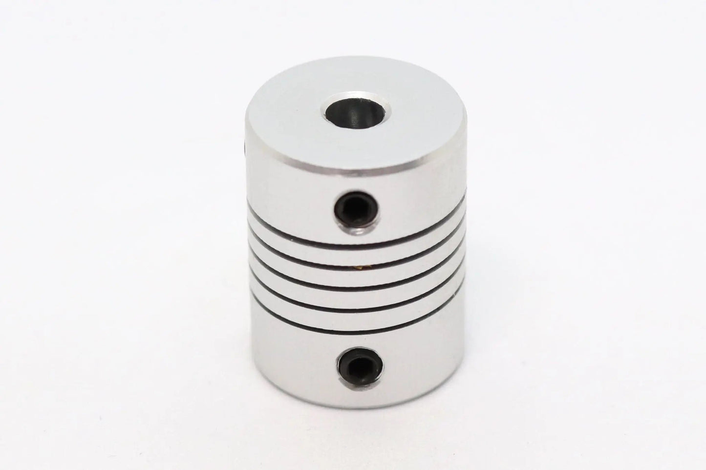 Accouplement flexible métallique cylindrique argenté, vu de face sur fond blanc