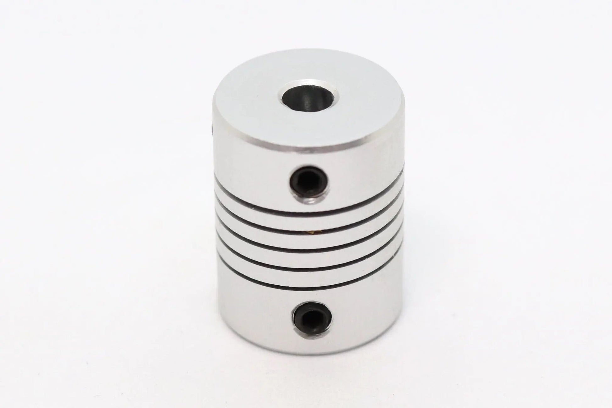 Accouplement flexible métallique cylindrique argenté, vu de face sur fond blanc