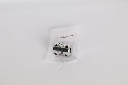Petit accouplement flexible métallique dans un sachet plastique, vu de face sur fond blanc