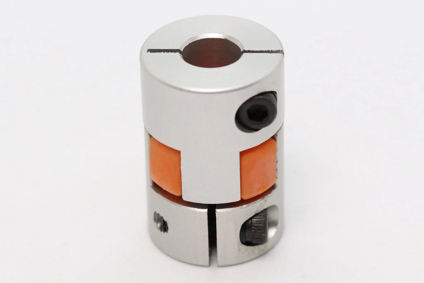 Accouplement d’arbre flexible métallique argenté avec insert orange, vu de face sur fond blanc