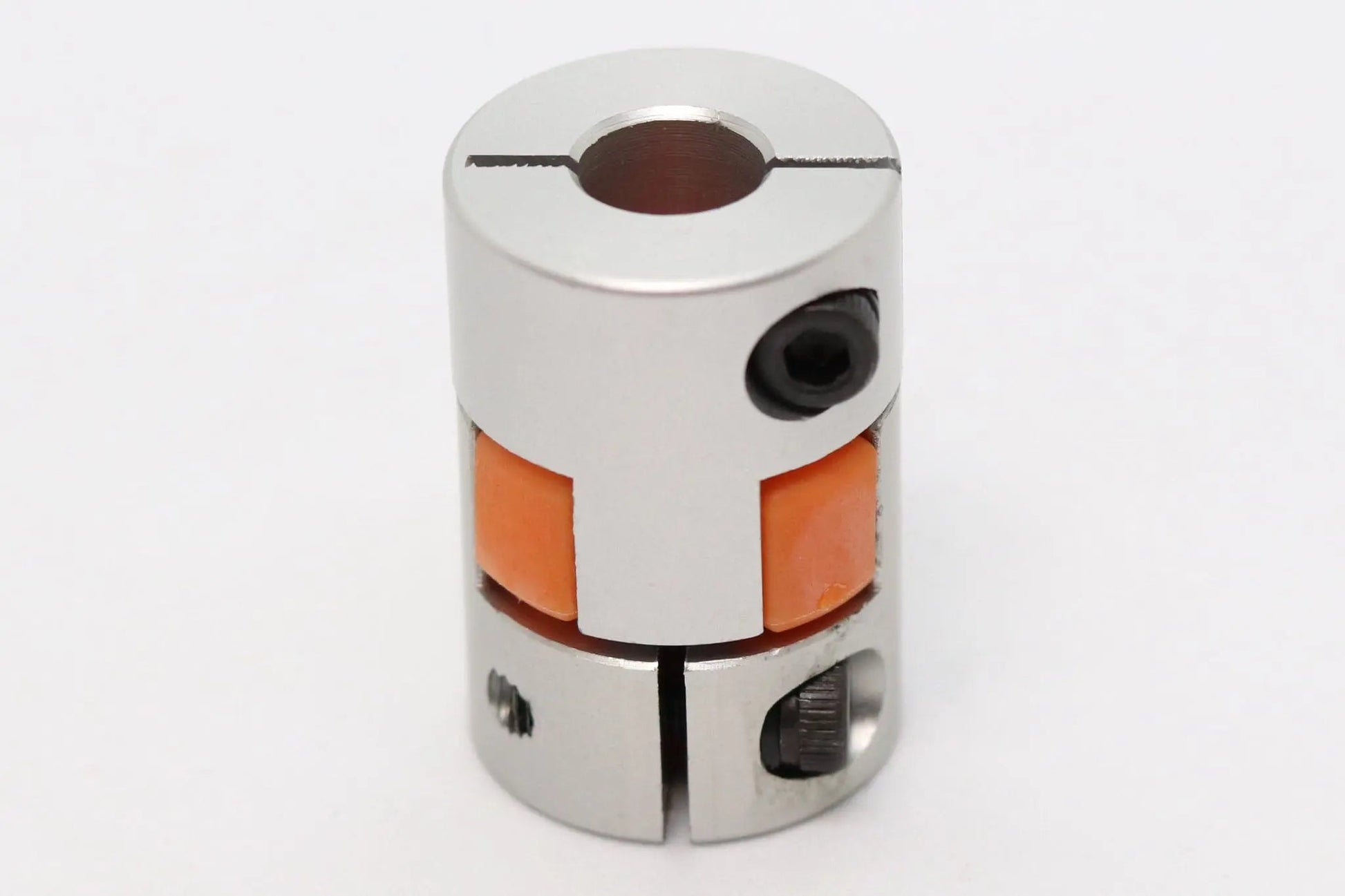 Accouplement d’arbre flexible métallique argenté avec insert orange, vu de face sur fond blanc