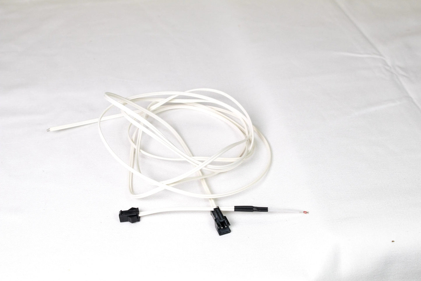 Câble thermistor blanc enroulé avec deux connecteurs noirs, posé sur fond blanc