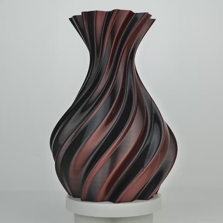 Vase imprimé en 3D torsadé, rouge et noir, posé sur un socle blanc