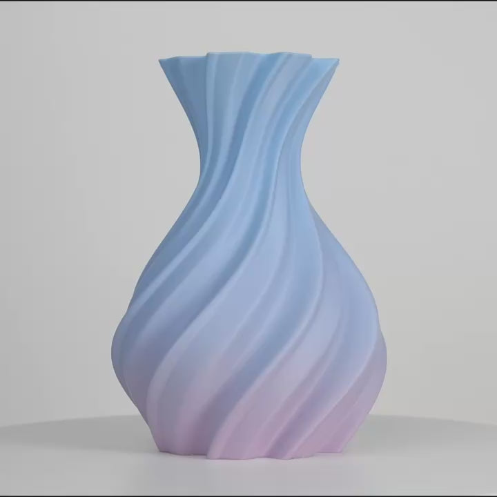 Vase spiralé aux dégradés bleu et rose, centré sur fond gris